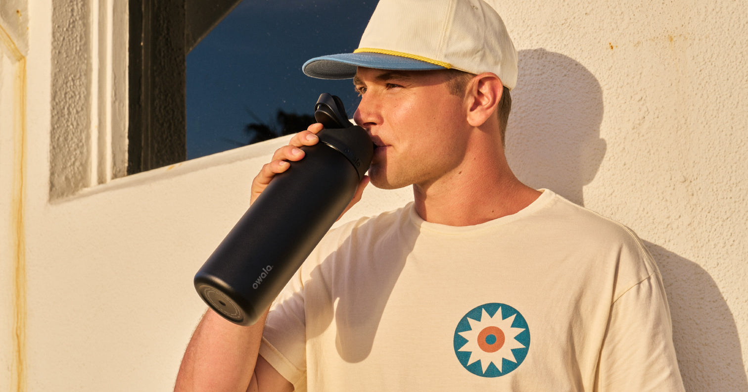 young man drinking water from a black water bottle