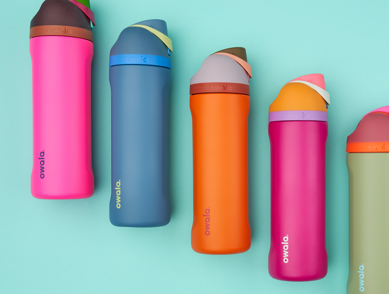 Lineup of five vibrant, colorful Owala 24oz FreeSip water bottles, diagonally set against a bright teal backdrop. Leak-proof, reusable drinkware for hydration, fitness, and eco-conscious lifestyles.